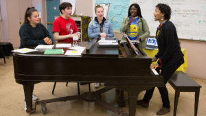 Teachers plays piano while her students watch